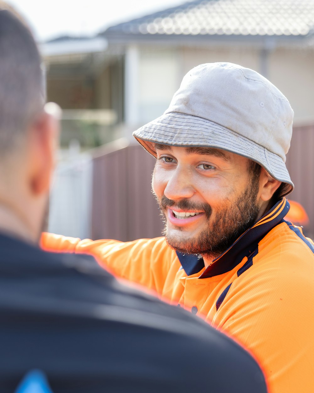 Un artisan en gilet de chantier sourit à un collègue