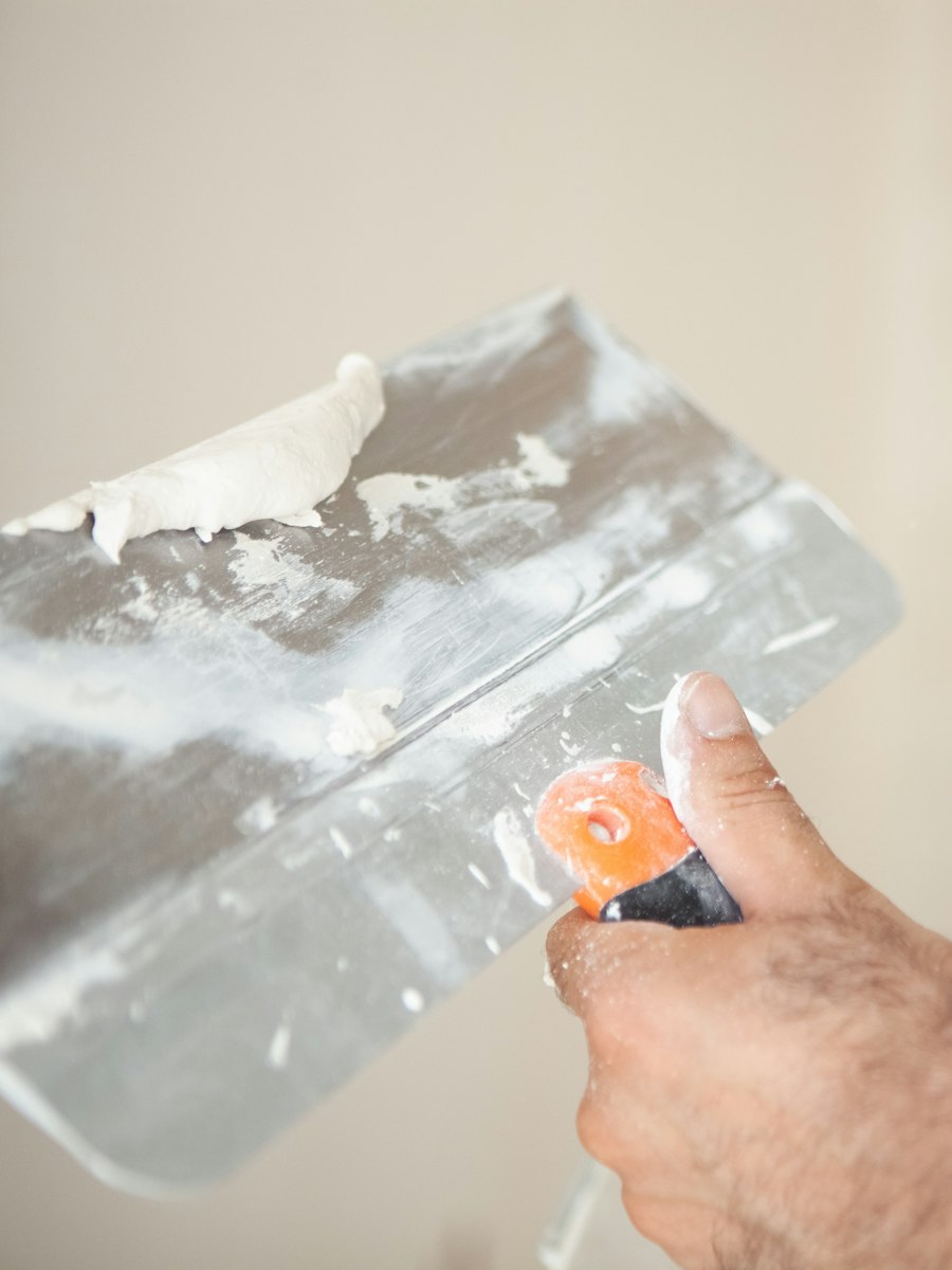 Des mains lissent un enduit au couteau